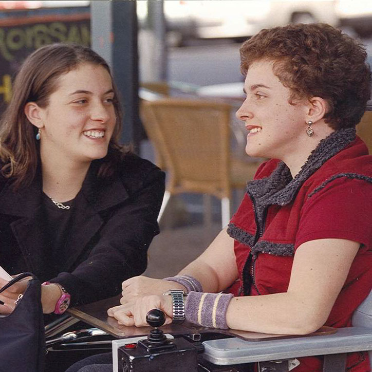 Image of two young women siting together smiling.