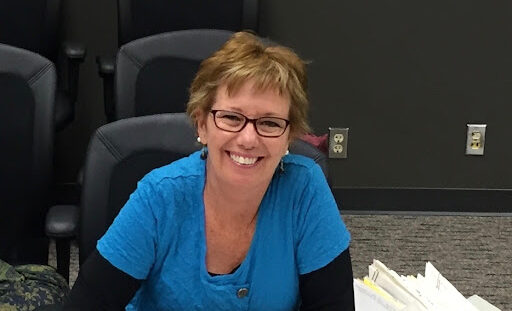 Jane Sherwin seated at table smiling.